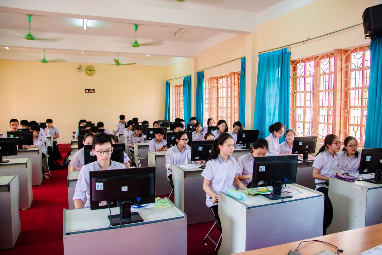 Asian students in uniform learning in a computer lab, focused on their tasks.